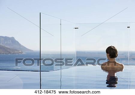 Woman in infinity pool enjoying ocean view View Large Photo Image Stock Photography - Woman in infinity pool enjoying ocean view. Fotosearch