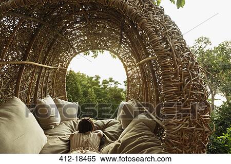 Stock Photography - Woman laying in nest tree house. Fotosearch
