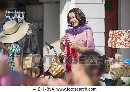 Picture - Woman trying on feather boa at yard sale. Fotosearch