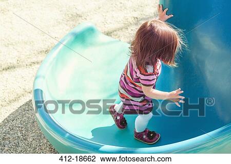 Baby girl climbing slide at playground View Large Photo Image Stock Image - Baby girl climbing slide at playground. Fotosearch