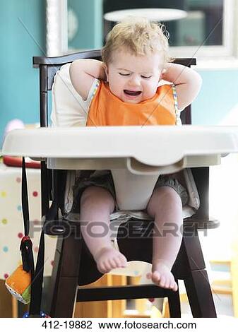 Stock Image - Baby girl crying in high chair. Fotosearch