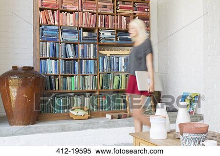 Blurred view of woman walking by book shelves View Large Photo Image Stock Photography - Blurred view of woman walking by book shelves. Fotosearch