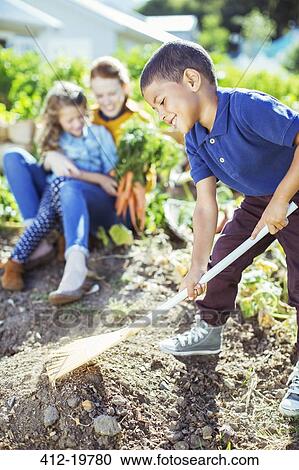 Boy turning over soil in garden View Large Photo Image Stock Image - Boy turning over soil in garden. Fotosearch