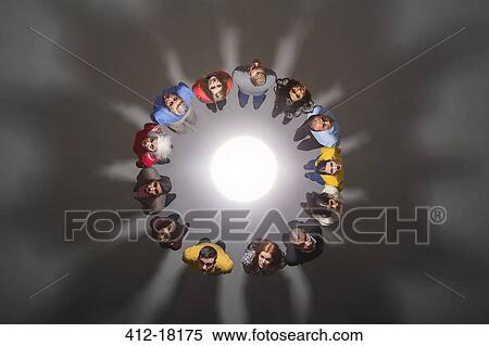Stock Photography - Business people around bright light. Fotosearch