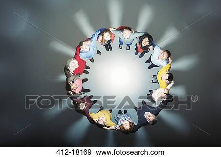 Business people forming huddle around bright light View Large Photo Image Stock Photo - Business people forming huddle around bright light. Fotosearch