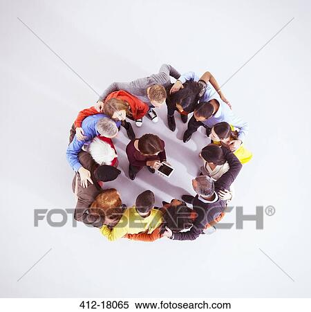 Stock Photography - Business people huddled around woman with digital tablet. Fotosearch