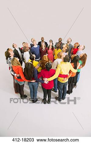 Stock Image - Business people looking up in huddle. Fotosearch