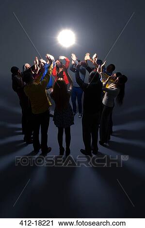 Stock Image - Business people shielding eyes from bright light. Fotosearch