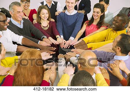 Stock Image - Business people with arms outstretched in huddle. Fotosearch