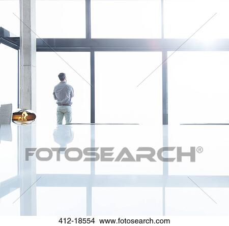 Businessman standing at office window View Large Photo Image Picture - Businessman standing at office window. Fotosearch