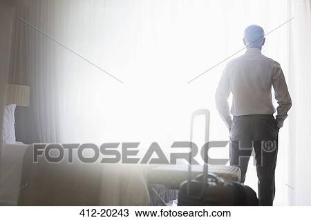 Stock Image - Businessman standing in hotel room. Fotosearch