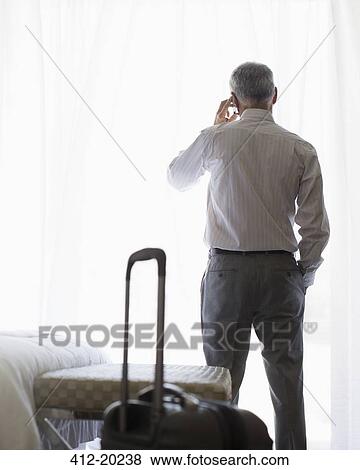 Businessman talking on cell phone in hotel room View Large Photo Image Stock Photo - Businessman talking on cell phone in hotel room. Fotosearch