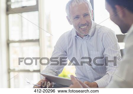 Stock Photograph - Businessmen laughing together in office. Fotosearch
