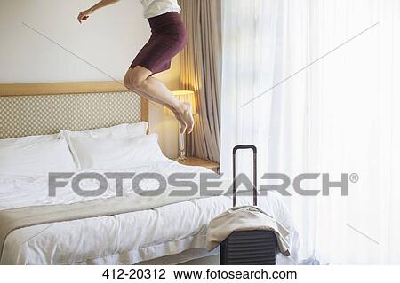 Businesswoman jumping on bed in hotel room View Large Photo Image Stock Image - Businesswoman jumping on bed in hotel room. Fotosearch