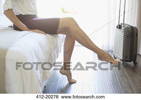 Stock Photo - Businesswoman taking shoes off in hotel room. Fotosearch