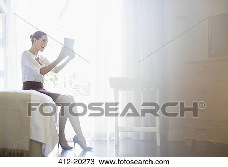 Stock Image - Businesswoman using digital tablet in hotel room. Fotosearch