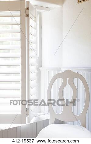 Stock Photo - Chair by window with wooden blinds. Fotosearch