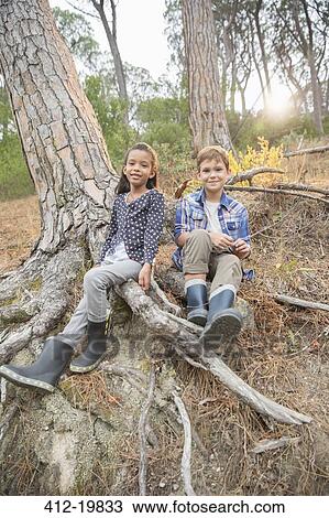 Children sitting on tree roots in forest View Large Photo Image Stock Image - Children sitting on tree roots in forest. Fotosearch