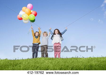 Children with balloons cheering on grassy hill View Large Photo Image Stock Image - Children with balloons cheering on grassy hill. Fotosearch