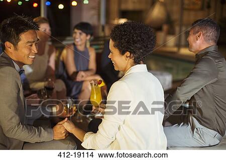 Picture - Couple holding hands at party. Fotosearch