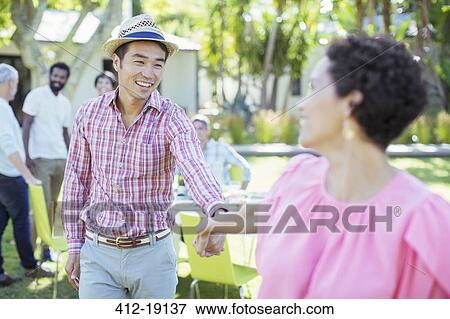 Stock Photo - Couple holding hands at party. Fotosearch