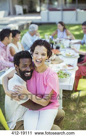 Stock Image - Couple hugging at table outdoors. Fotosearch