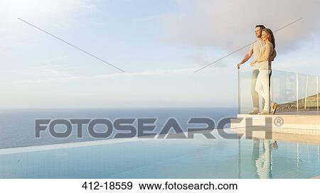 Couple overlooking ocean from modern balcony View Large Photo Image Stock Photo - Couple overlooking ocean from modern balcony. Fotosearch