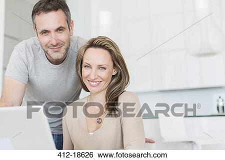 Couple smiling at laptop View Large Photo Image Stock Photograph - Couple smiling at laptop. Fotosearch
