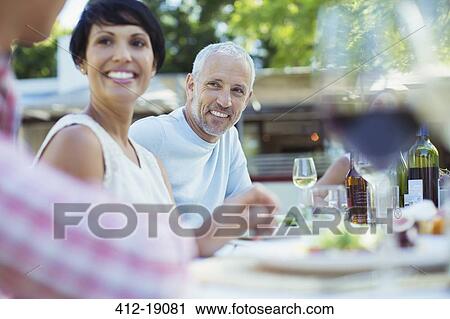Stock Image - Couple smiling at table outdoors. Fotosearch