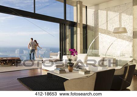 Stock Image - Couple standing on balcony of modern house. Fotosearch