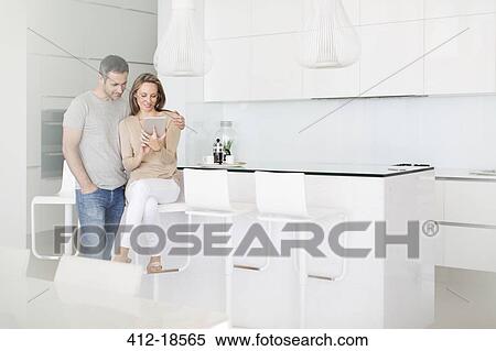 Couple using digital tablet in kitchen View Large Photo Image Stock Photography - Couple using digital tablet in kitchen. Fotosearch