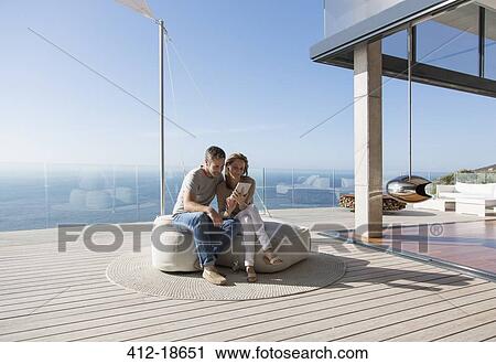 Stock Image - Couple using digital tablet on modern balcony. Fotosearch