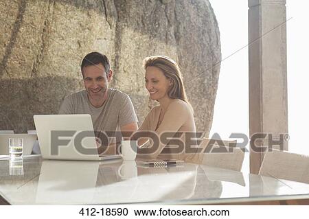 Stock Image - Couple using laptop at breakfast. Fotosearch