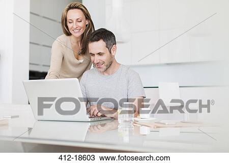 Couple using laptop at breakfast table View Large Photo Image Stock Image - Couple using laptop at breakfast table. Fotosearch