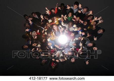 Diverse crowd cheering around bright light View Large Photo Image Stock Photo - Diverse crowd cheering around bright light. Fotosearch