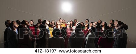 Stock Photo - Diverse crowd looking up at bright light. Fotosearch