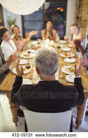 Stock Image - Friends applauding at dinner party. Fotosearch