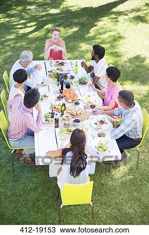 Friends eating together at table outdoors View Large Photo Image Stock Image - Friends eating together at table outdoors. Fotosearch