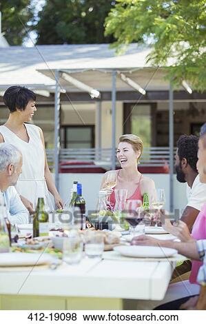 Friends eating together at table outdoors View Large Photo Image Stock Photo - Friends eating together at table outdoors. Fotosearch