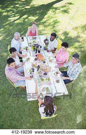 Friends eating together at table outdoors View Large Photo Image Stock Photo - Friends eating together at table outdoors. Fotosearch