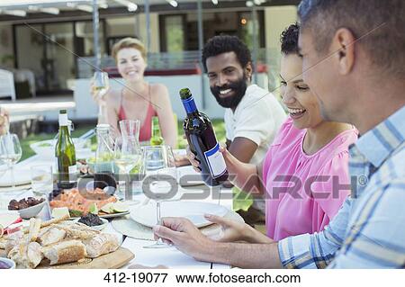 Stock Photo - Friends eating together outdoors. Fotosearch