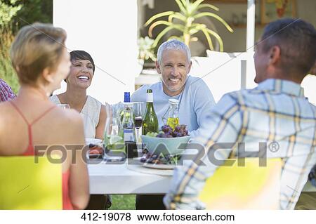 Stock Photo - Friends eating together outdoors. Fotosearch