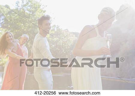 Stock Photograph - Friends holding hands by pool. Fotosearch