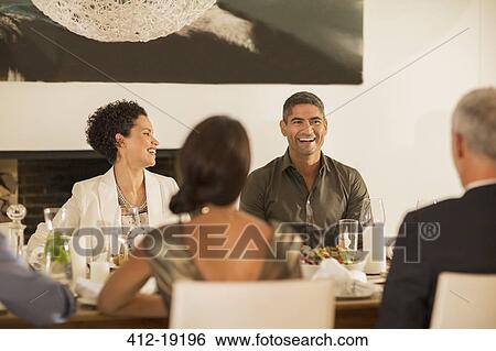 Stock Photograph - Friends laughing at dinner party. Fotosearch