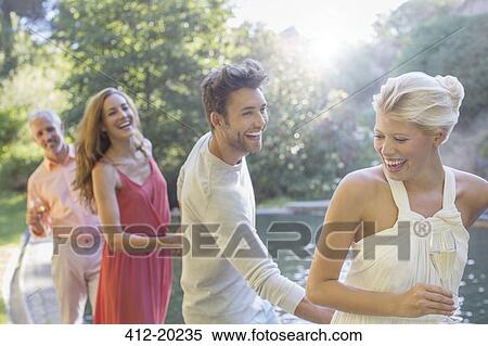Stock Photography - Friends playing by pool. Fotosearch