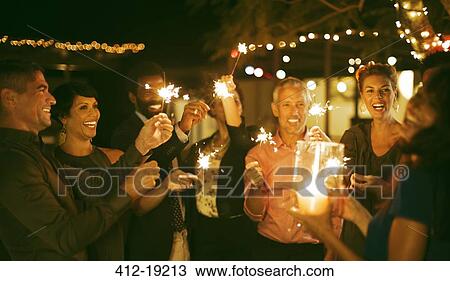 Friends playing with sparklers at party View Large Photo Image Stock Image - Friends playing with sparklers at party. Fotosearch