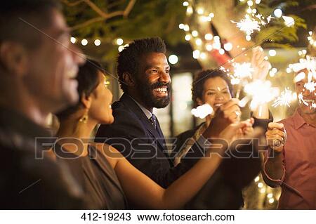 Stock Image - Friends playing with sparklers at party. Fotosearch