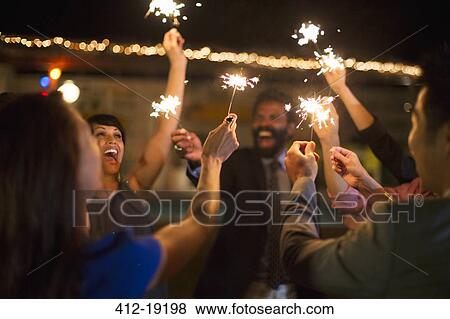 Stock Photo - Friends playing with sparklers at party. Fotosearch