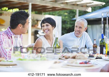 Friends relaxing at table outdoors View Large Photo Image Stock Image - Friends relaxing at table outdoors. Fotosearch