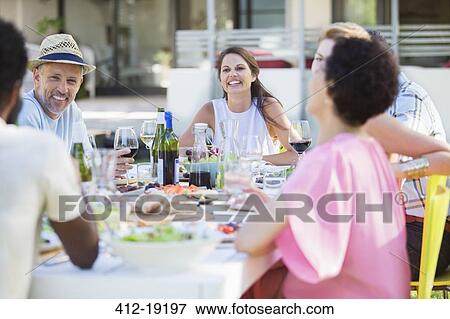 Stock Photo - Friends relaxing at table outdoors. Fotosearch